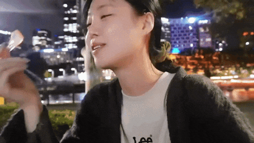 a woman wearing a lee t-shirt is eating food at night