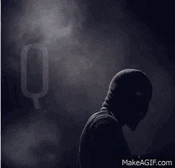 a silhouette of a man wearing a mask with the letter q behind him
