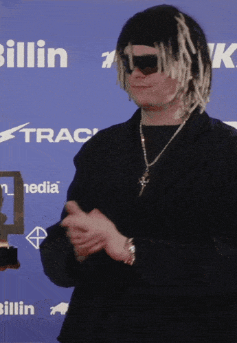 a man wearing a wig and sunglasses is clapping in front of a blue background that says billin