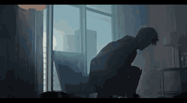 a man is kneeling down in front of a large window