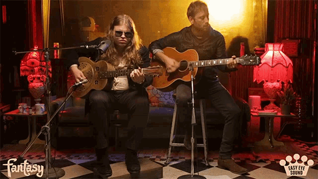 two men playing guitars in front of a microphone with the words fantasy on the bottom