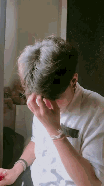 a young man is covering his face with his hands