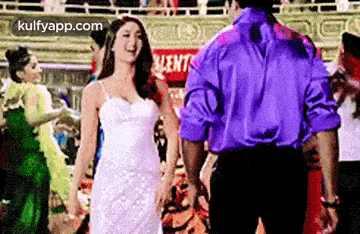 a man in a purple shirt is holding a woman in a white dress .