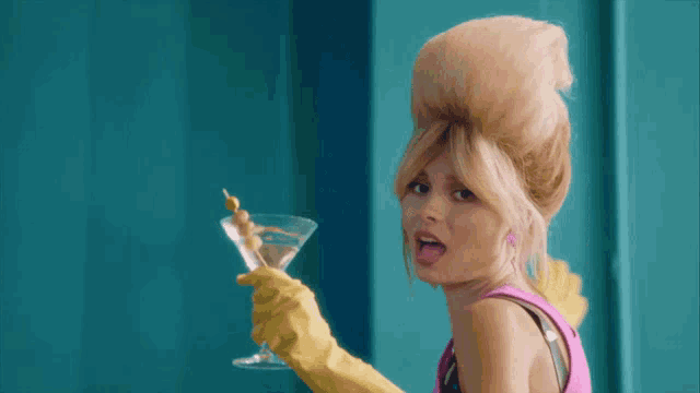 a woman in a pink top and yellow gloves holds a martini glass