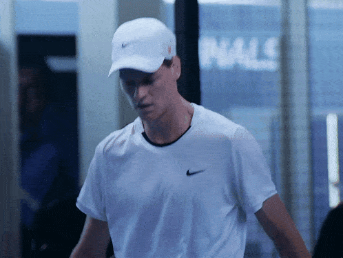a man wearing a white nike shirt and a white cap