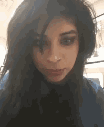 a close up of a woman 's face with long hair and a blue shirt .
