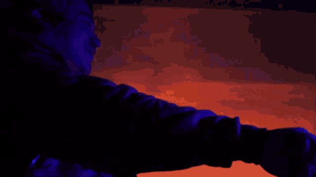 a person in a dark room with a bottle in front of them