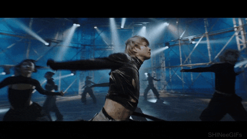 a group of people are dancing in a dark room with shinee gifs written on the bottom