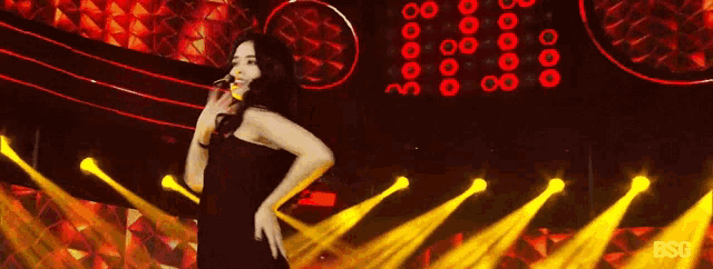 a woman in a black dress is dancing on a stage in front of a sign that says 30000