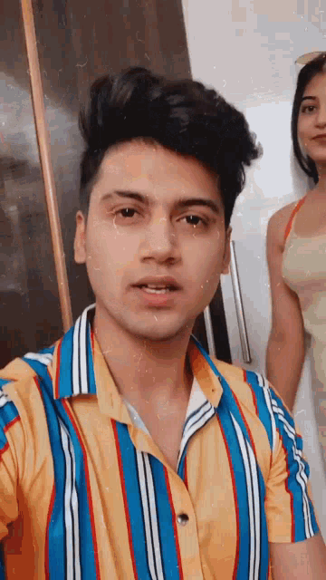 a young man in a striped shirt takes a selfie