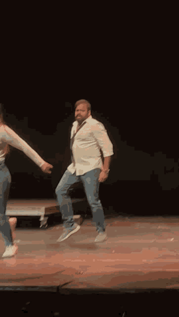 a man in a white shirt is dancing with a woman