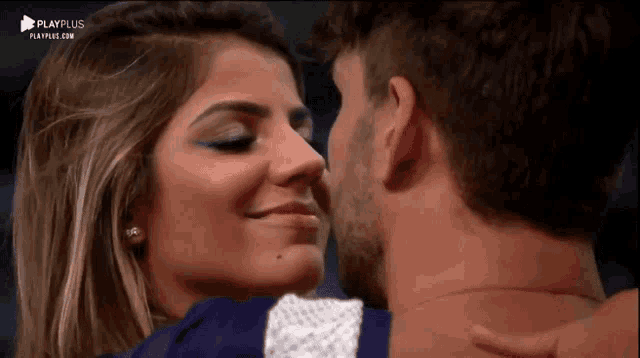 a man and a woman are kissing in front of a screen that says playplus
