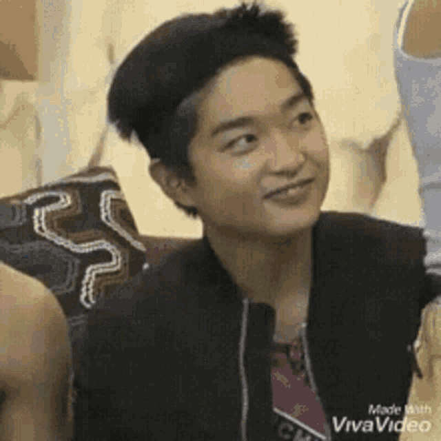 a young man is smiling while sitting on a couch with other people .