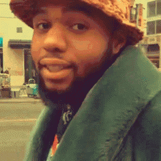 a man with a beard is wearing a hat and a green coat