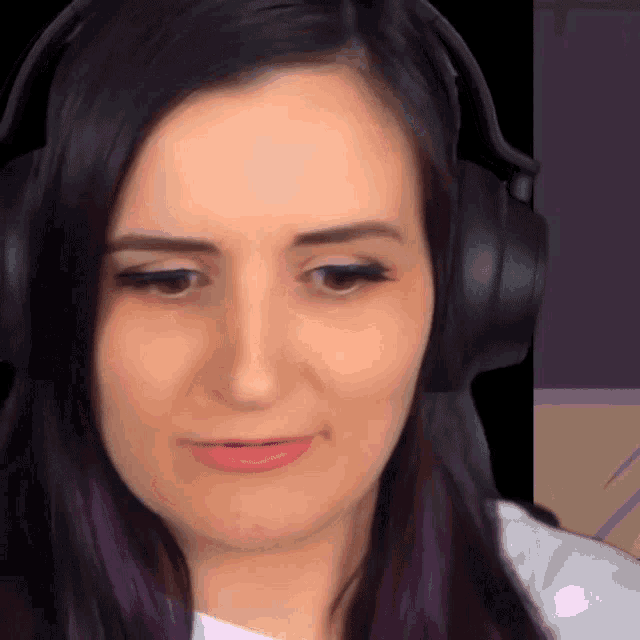 a woman with purple hair wearing headphones looks at the camera
