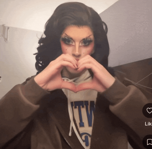a woman making a heart shape with her hands while wearing a sweatshirt that says tv