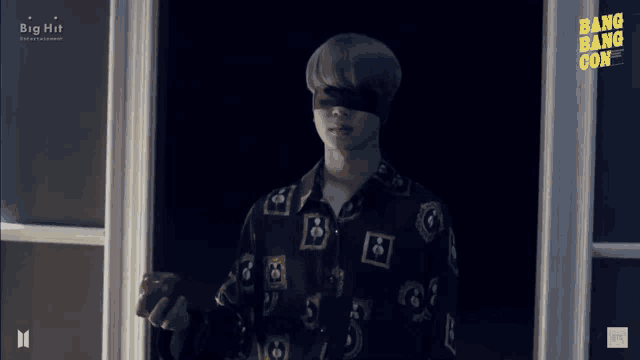a man wearing a blindfold is holding an apple in front of a window ..