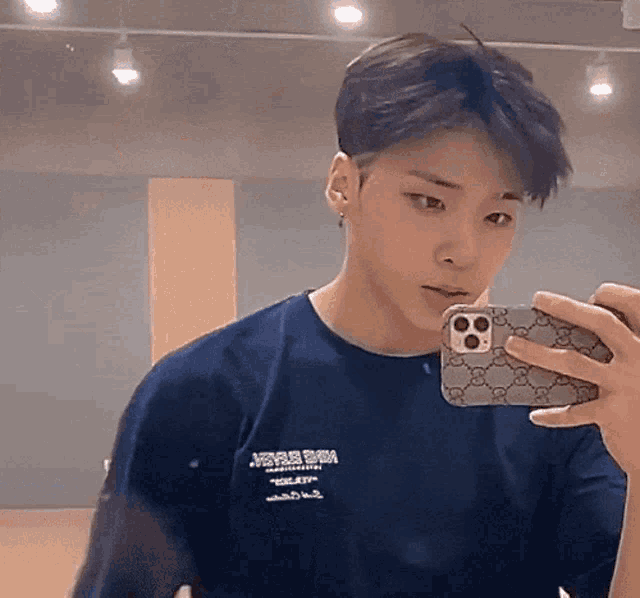a young man in a blue shirt is taking a picture of himself in a mirror