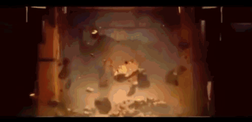 a person is laying on the floor in a dark room with a lot of rocks flying around .