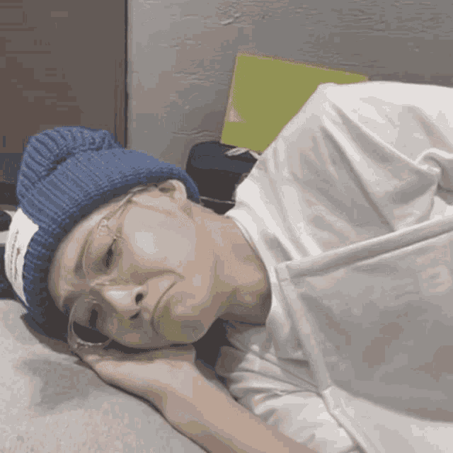 a person wearing a blue hat and glasses is laying down