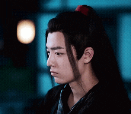 a close up of a young man 's face with long hair and a red ponytail .