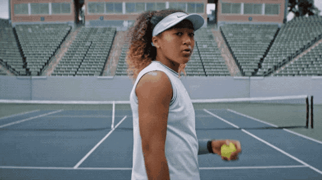 a woman is holding a tennis ball on a court