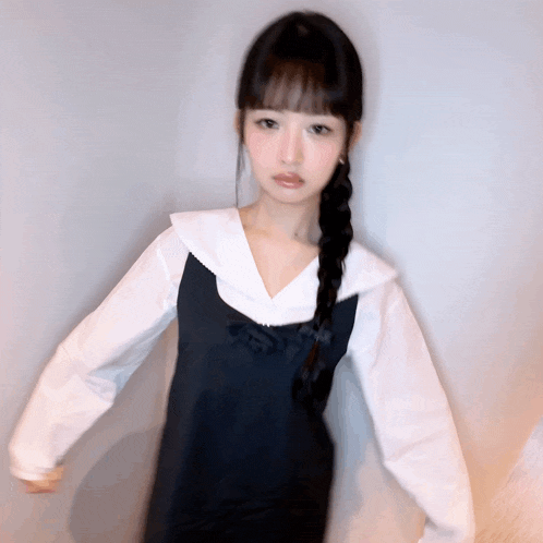 a girl wearing a black dress and a white shirt has a braid in her hair