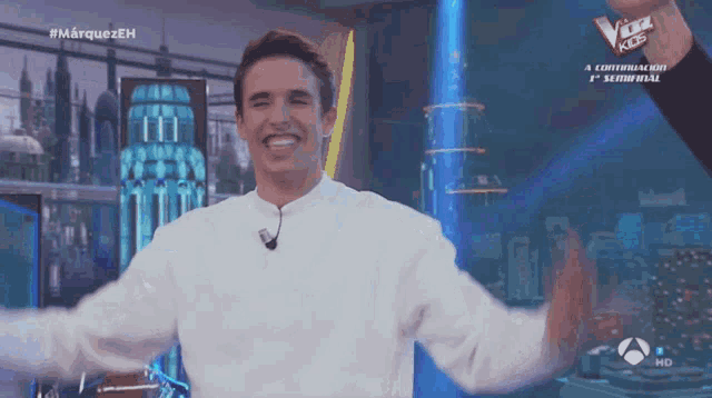 a man in a white shirt stands on a stage with his arms outstretched in front of a sign that says the voice kids