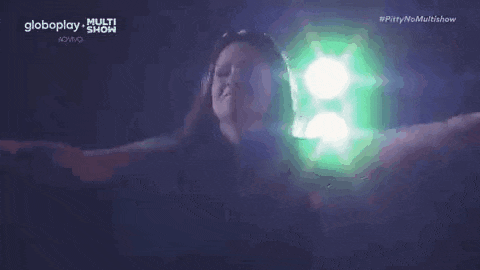 a woman is singing into a microphone on a stage in front of a green light .