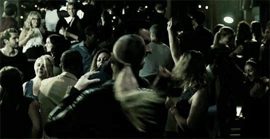 a crowd of people are dancing in a dark room at a party .