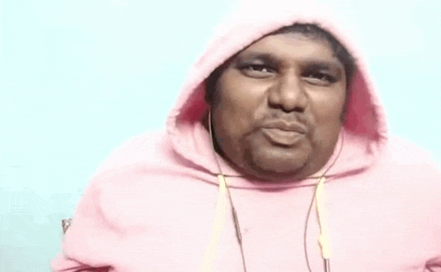 a man wearing a pink hoodie and headphones is making a funny face and says avunu .