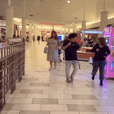 people walking in a mall with a pink claw machine