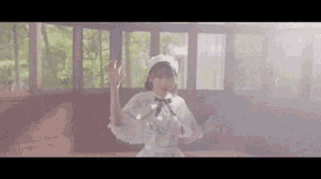 a woman in a white dress and hat is dancing in a room with a lot of windows .