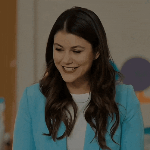 a woman in a blue jacket and white shirt smiles for the camera