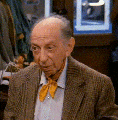 an elderly man wearing a plaid jacket and a yellow tie