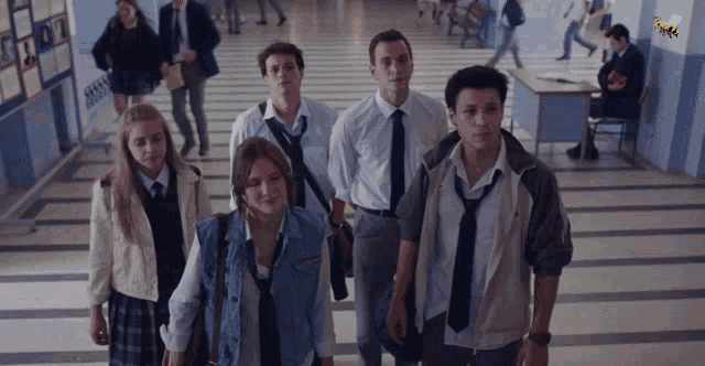 a group of students walking down a hallway with a bee on the wall behind them