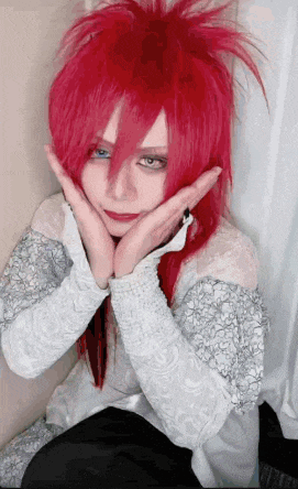 a girl with red hair and blue eyes is making a face with her hands