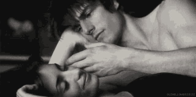 a man is touching a woman 's forehead while she sleeps in a black and white photo .