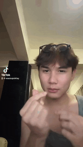 a young man wearing sunglasses making a heart shape with his hands .