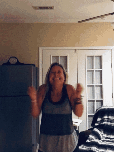 a woman is dancing in front of a refrigerator in a room