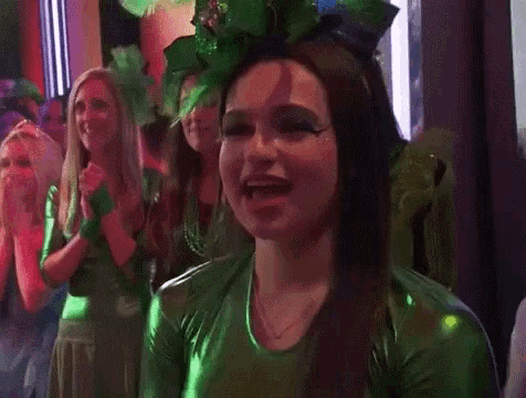 a woman in a green outfit is standing in front of a group of women in green outfits .