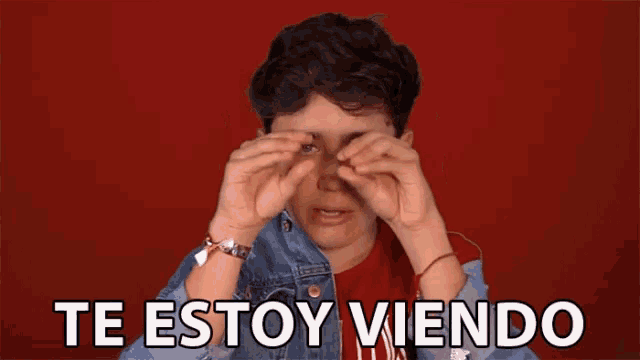 a person is covering their eyes with their hands and the words te estoy viendo are written below them
