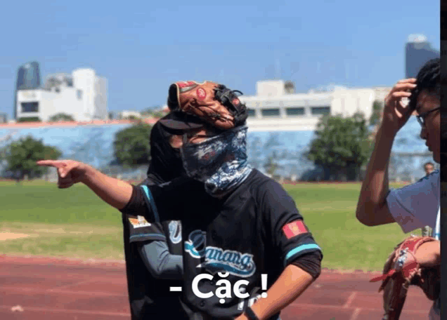 a man with a baseball glove on his head is wearing a shirt that says các