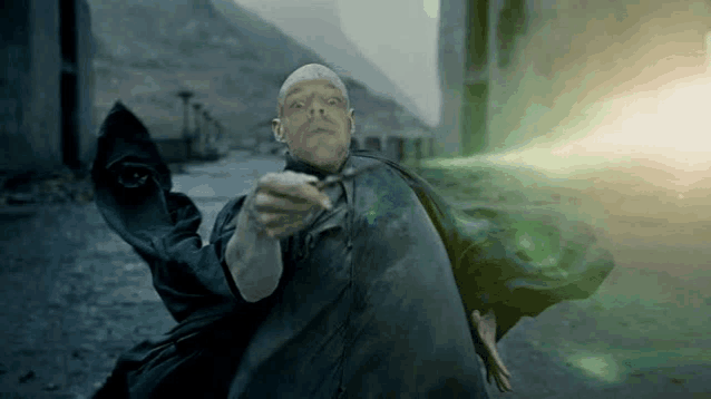 a bald man in a cape is casting a spell with a green light coming out of his hand