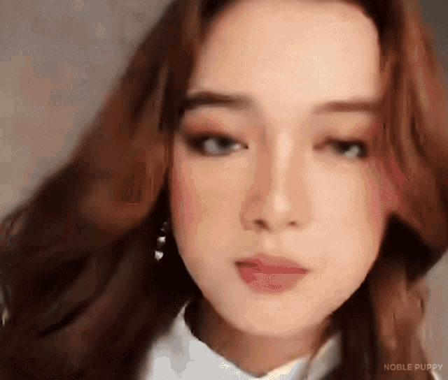 a close up of a woman 's face with a white shirt on and earrings .