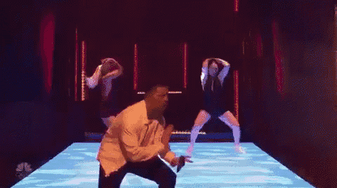 a man and two women are dancing on a stage in a dark room