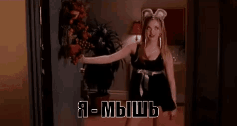 a woman wearing bunny ears and a black dress is standing in a room .