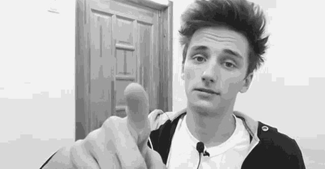 a young man is giving a thumbs up sign in front of a door .