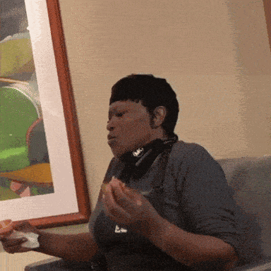 a woman wearing a mask is sitting in front of a picture