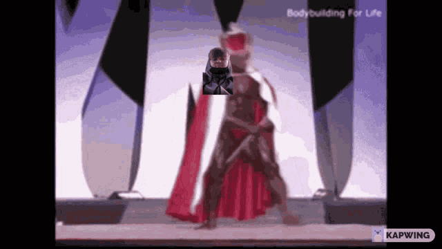 a man in a red cape is standing on a stage with the words bodybuilding for life behind him